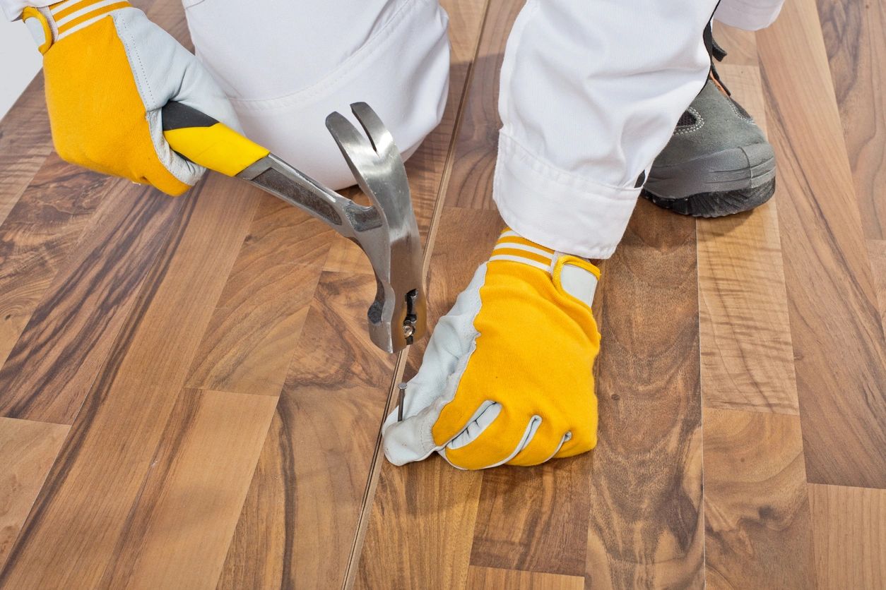 A person with gloves on holding pliers and a hammer.